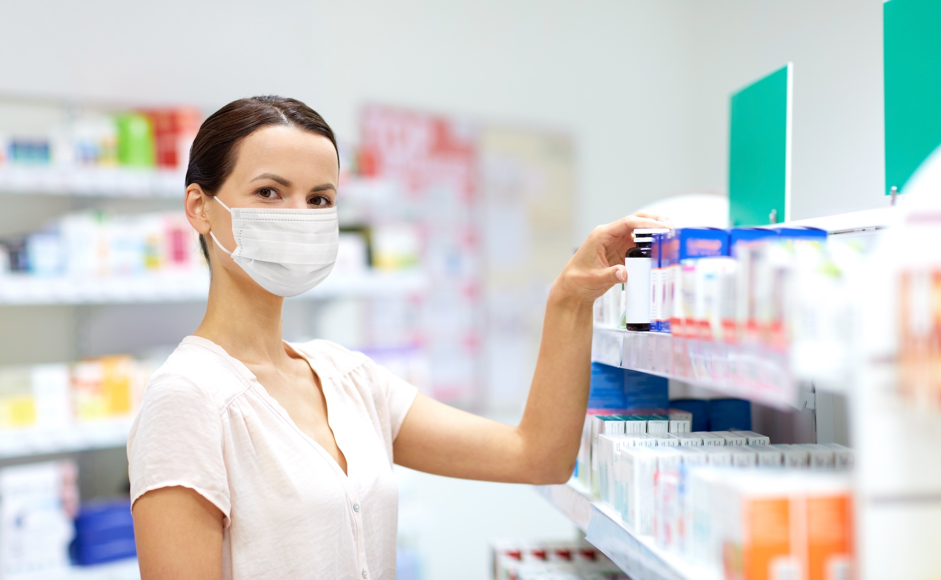 female customer in mask choosing drugs at pharmacy